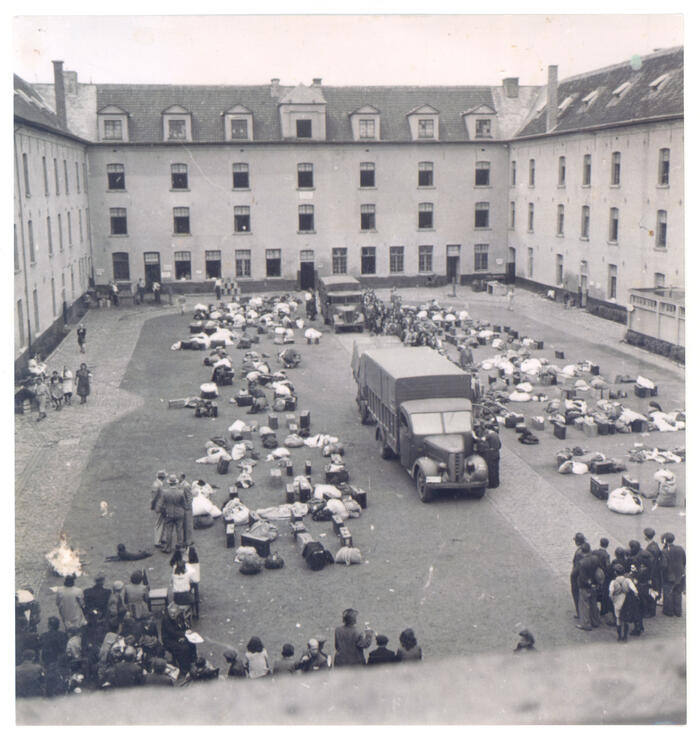 Possessions are stacked in the courtyard of the Dossin Barracks, there is a lorry in the centre of the courtyard