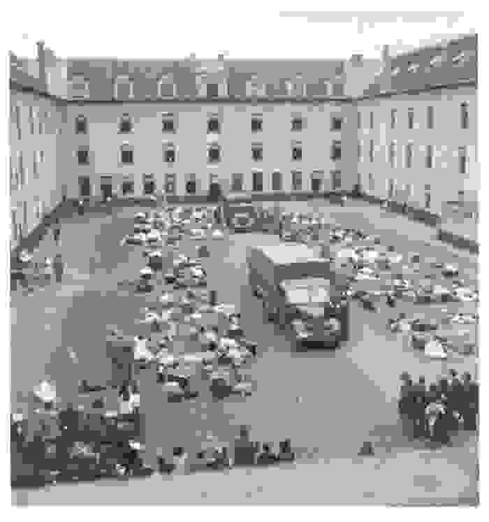 Possessions are stacked in the courtyard of the Dossin Barracks, there is a lorry in the centre of the courtyard