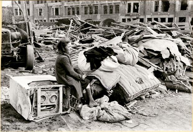 A woman is sitting on an appliance among the rubble after the bombing raid on Mortsel