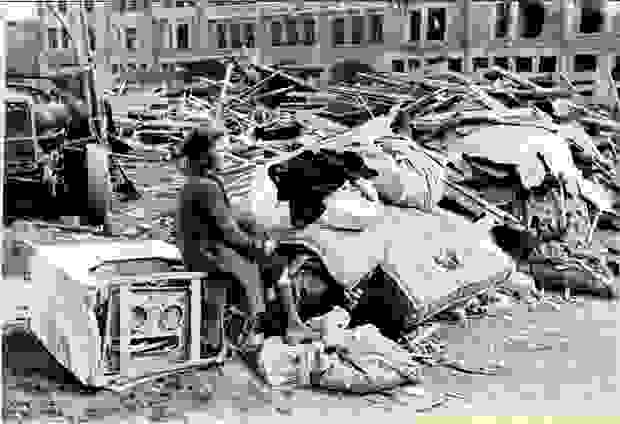 A woman is sitting on an appliance among the rubble after the bombing raid on Mortsel