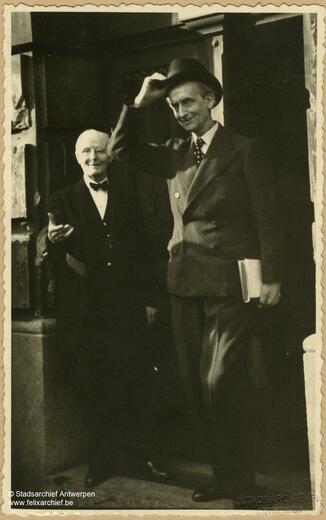 Camille Huysmans grabs his hat, a man stands next to him